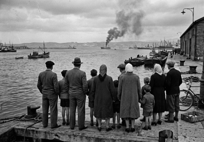 Curiosos reunidos en el muelle observando arder el barco